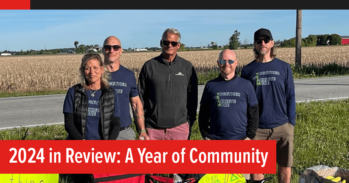 2024 in Review: A Year of Community – Bike to the Bay, The McAlear Group fans standing on the race sideline with their chairs, signs, and snacks, wearing "together we achieve more t-shirts"