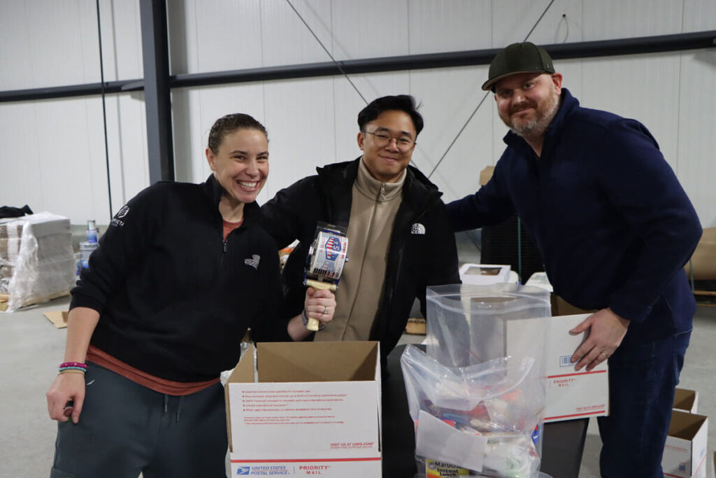 SSC team members smiling together, packing boxes with goods for Operation Holiday Drop