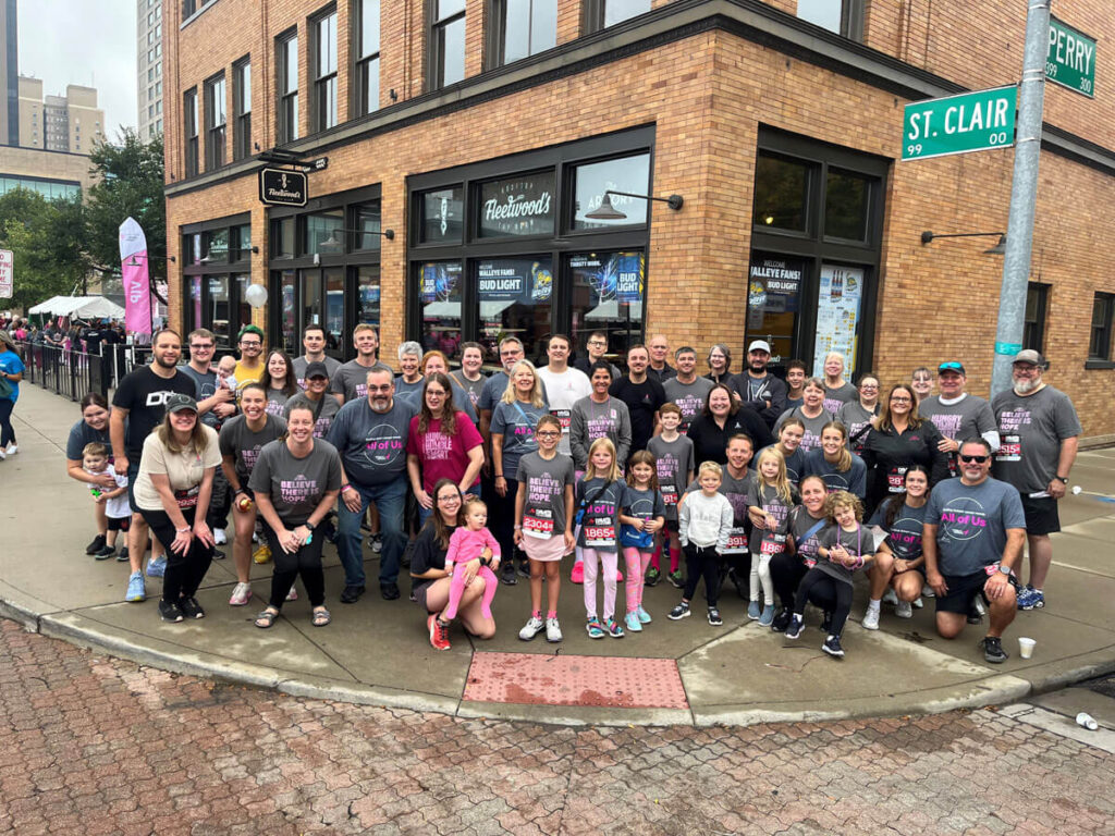 Group of SSC team member racers standing on corner street with "All of Us" t-shirts on 