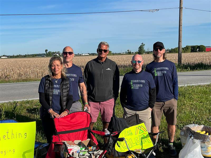 Bike to the Bay, The McAlear Group fans standing on the race sideline with their chairs, signs, and snacks, wearing "together we achieve more t-shirts"